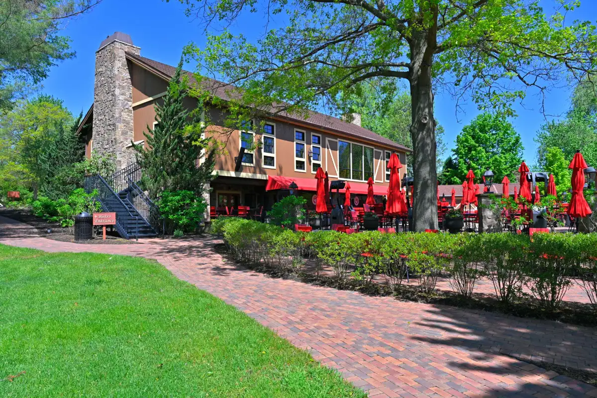 Exterior of Gervasi Vineyard restaurant with stone chimney, brick patio, and red umbrellas for outdoor dining. Sugarcreek Builder’s custom renovation blends rustic charm with modern hospitality design.