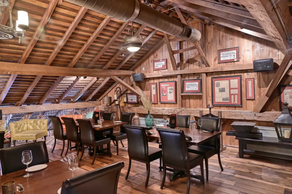 Cozy loft dining area at Gervasi Vineyard with exposed wood beams, framed decor, leather chairs, and rustic timber frame construction. Sugarcreek Builder’s detail work creates an intimate hospitality space.